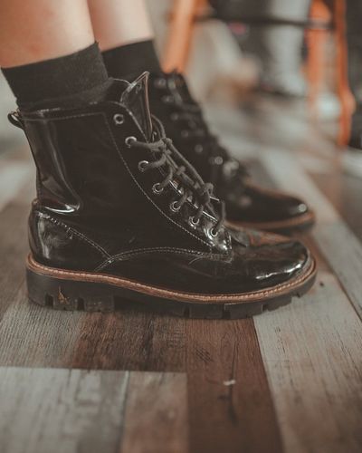 Close-up of a person's running shoes on a wooden floor.